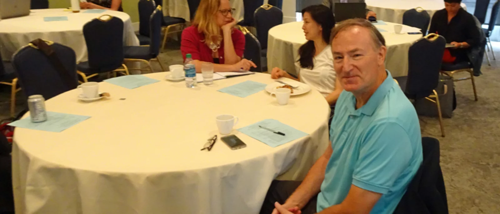 Ron Hays sitting at a table in blue shirt at 2018 Research Symposium.